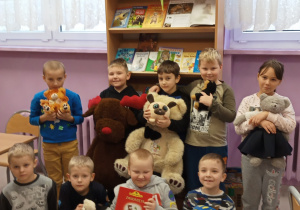 Uczniowie trzymający własne misie w szkolnej bibliotece