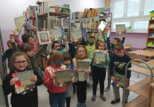 Grupa dzieci w bibliotece, w rękach trzymają książkę i zakładkę.