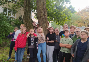 Uczniowie tulący się do drzewa.