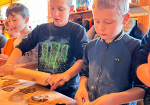 Uczniowie wałkują ciasto na pierniki