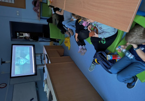 Uczniowie oglądający wieczorem seans filmowy w sali lekcyjnej.