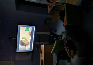 Uczniowie oglądający wieczorem seans filmowy w sali lekcyjnej.