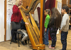 Uczniowie próbują grać na harfie