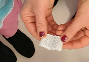 Dłonie trzymające najmniejszą książkę w bibliotece