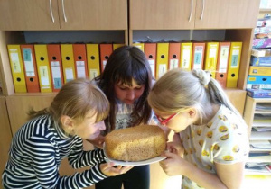 Trzy dziewczynki wąchają upieczony przed chwilą chleb.