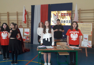 Uczniowie klasy 7a w trakcie śpiewania pieśni patriotycznej, stojący na baczność
