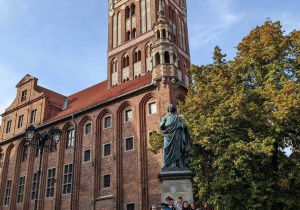 Uczestnicy wycieczki pod pomnikiem Mikołaja Kopernika w Toruniu